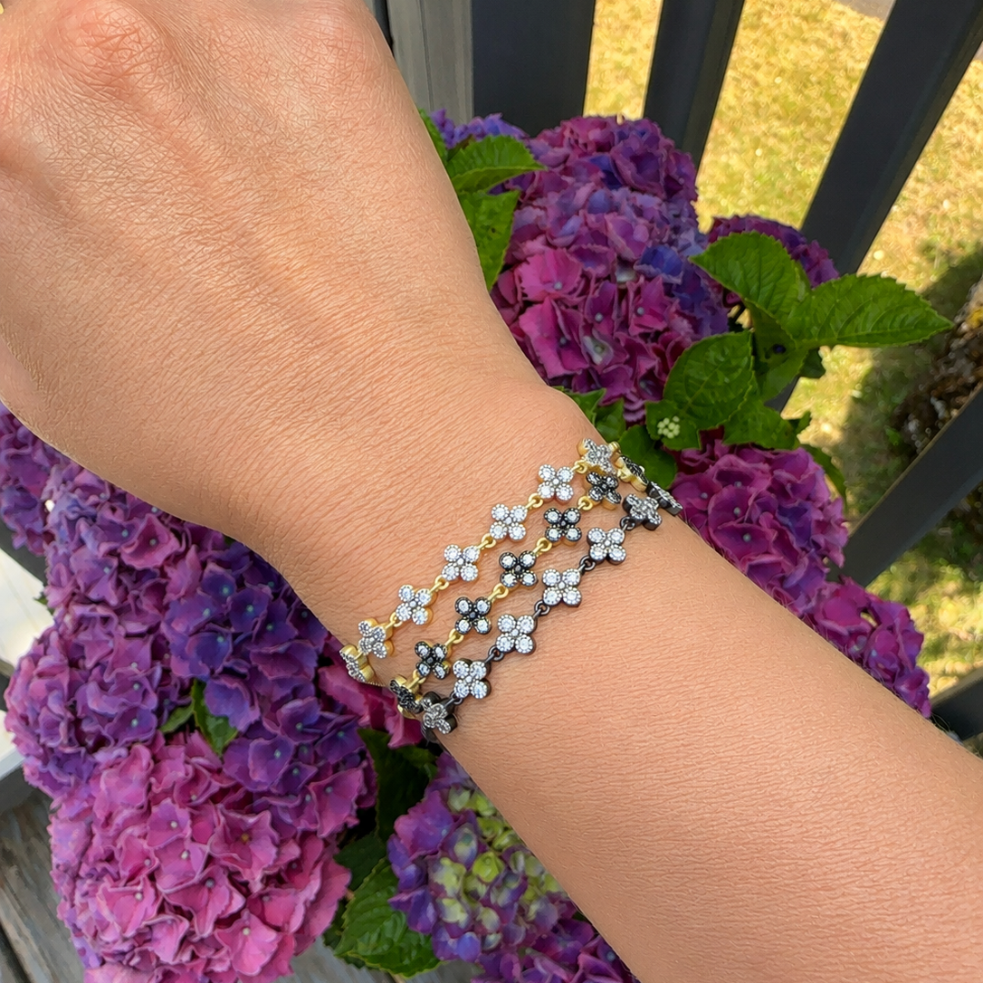 A silver-toned double-strand bracelet with small flower charms, worn on a person&
